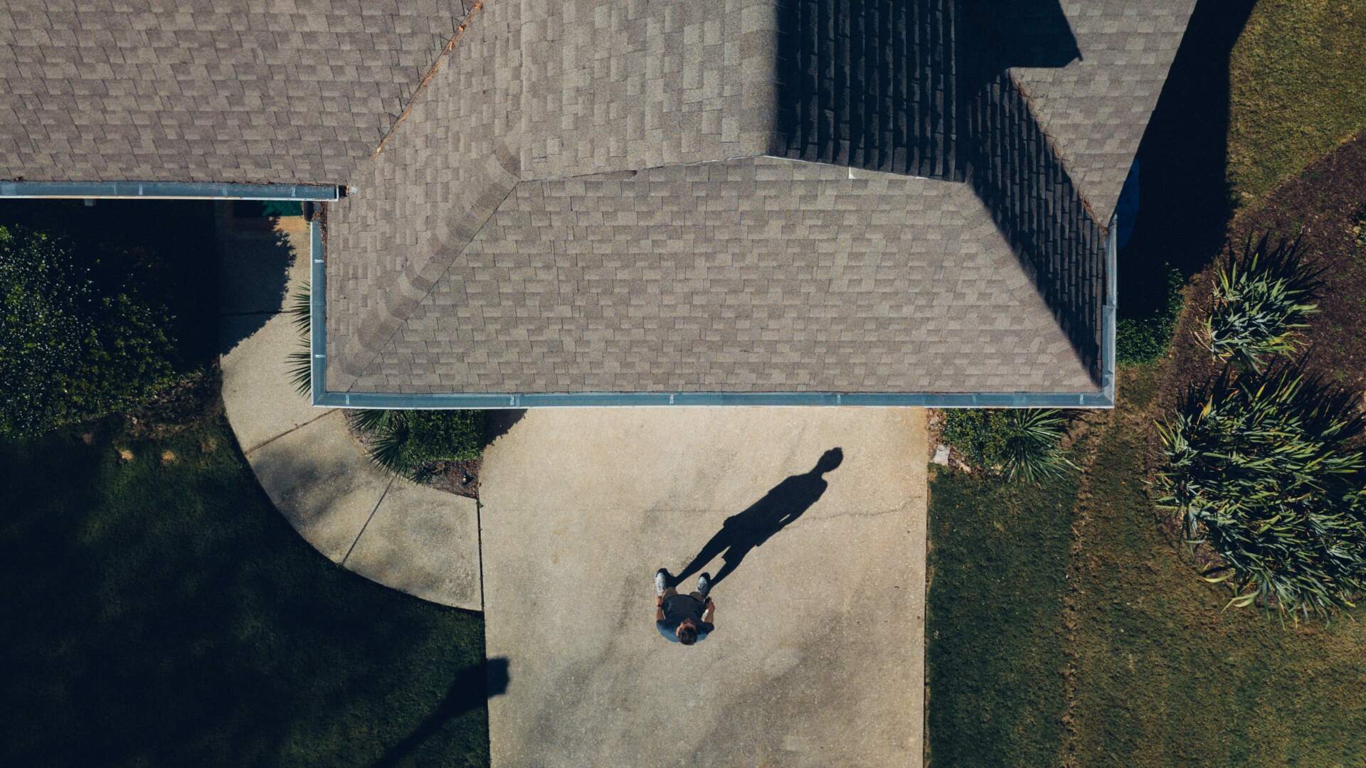 Overhead view of homeowners walking toward home with gutters.